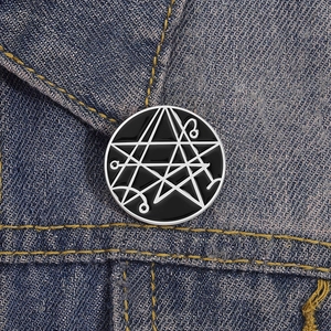 Spilla in smalto nero con simboli geometrici su colletto di denim, design creativo