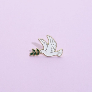 Détail d'un pin's en émail colombe blanche avec branche d'olivier et bordure dorée