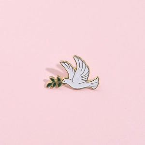 Détail d'une broche en émail de colombe blanche avec rameau d'olivier vert et bords dorés