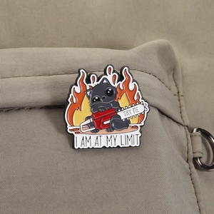 Funny enamel black cat pin with chainsaw and flames on a canvas bag detail view