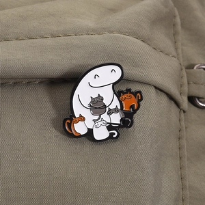 Cartoon enamel pin of a Flork character holding cats pinned on green canvas bag
