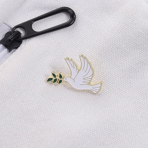 Gros plan d'une broche colombe de la paix en émail blanc avec rameau d'olivier sur toile