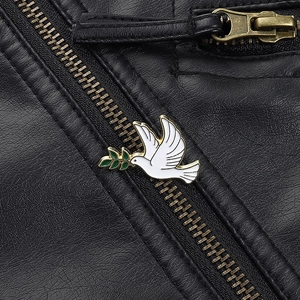 Détail d'un pin's colombe de la paix blanc avec branche d'olivier sur une veste en cuir