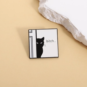Detailed close-up of a funny black cat enamel pin with bitch text on a beige surface