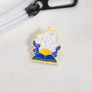 Detail of starry night magic book enamel pin with sun and stars on white canvas bag