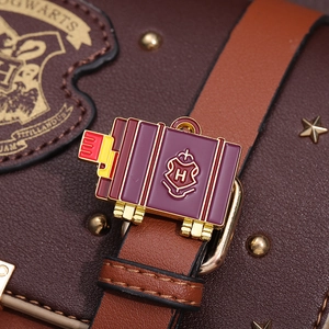 Detailed macro view of an enamel suitcase brooch with Hogwarts H crest on a leather bag