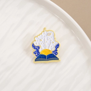 Detailed close-up of a blue starry sky magic book enamel pin with gold plating details