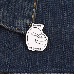 Close-up of 'Better Together' enamel pin with cartoon figures hugging on denim fabric