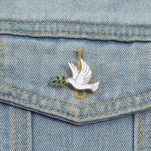 Gros plan d'une broche colombe de la paix en émail blanc sur une veste en jean bleu