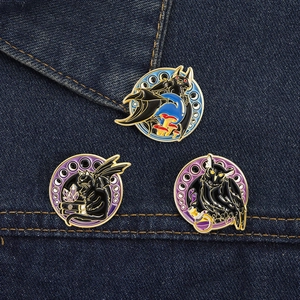 Detailed view of gothic black cat and owl enamel pins on dark blue denim jacket fabric