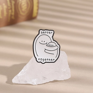 Minimalist enamel pin featuring white cartoon figures hugging with Better Together quote