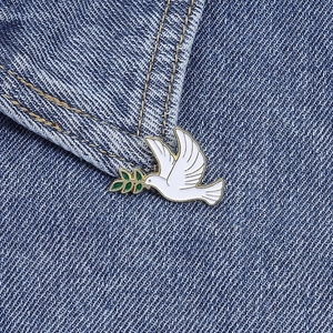 Broche colombe de la paix en émail blanc avec rameau d'olivier sur tissu denim
