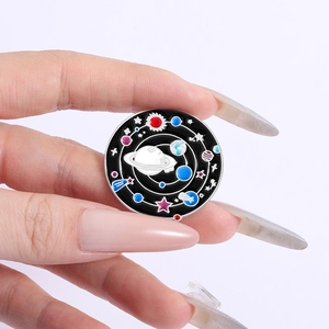 Cosmic universe enamel pin with colorful Saturn and stars on a black background