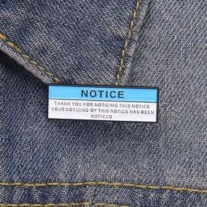 Creative enamel pin badge featuring Notice funny quotes on dark denim jacket background