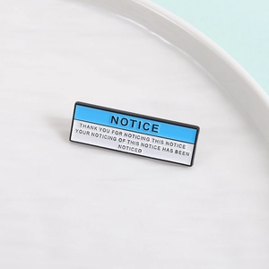 Macro shot of a rectangular enamel pin with blue and white humorous typography