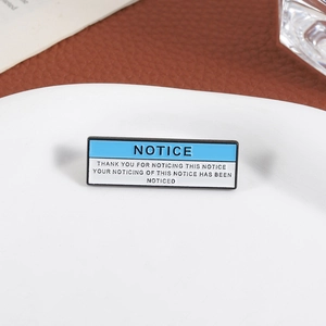 Detail of creative enamel notice pin badge placed on white ceramic plate background