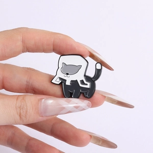 Kreative Emaille-Anstecknadel im schwarz-weißen Katzen-Design in der Hand