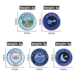 Detailed view of 5 assorted 4.4cm tinplate badges with music and astronomy illustrations