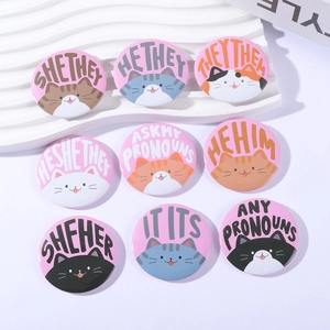 Detail of nine cartoon cat tinplate badges with pronouns arranged on white display board