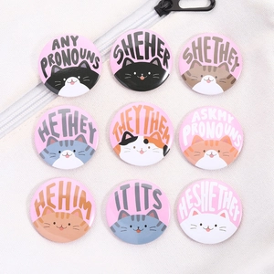 Set of 9 cute cartoon cat tinplate badges with gender pronouns on white canvas