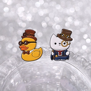 Detail view of steampunk duck and cat enamel lapel pins with gear and monocle accents