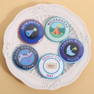 Five creative illustration tinplate badges with astronomical and musical themes on a plate