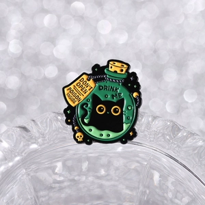 Detail of black cat potion bottle enamel pin with poison warning tag and skull charm
