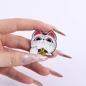 Gros plan détaillé d'un pin's chat porte-bonheur en émail avec une clochette jaune