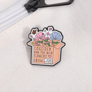 Detail of enamel pin with wild flowers in a box and 'Luke 12:27' quote on canvas