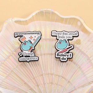 Detailed view of two funny blue frog enamel pins on a pearlescent decorative tray
