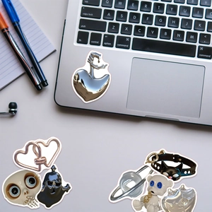 Detail of 3D metallic Halloween skull and heart stickers on a silver laptop surface
