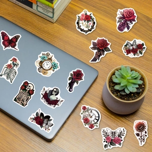 Gothic punk stickers with red roses and skulls applied on a laptop on a wooden desk
