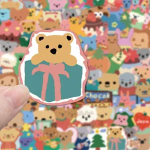 Cute cartoon brown bear sticker in blue gift box with pink bow for journals and iPads