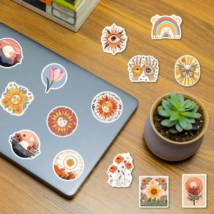 Bohemian sun and floral decorative stickers applied to a laptop on a wooden desk