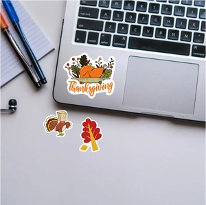 Close-up of Thanksgiving turkey and maple leaf stickers on a laptop surface