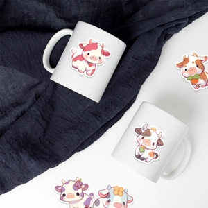 Close-up of cute cartoon cow stickers decorated on white ceramic mugs and table