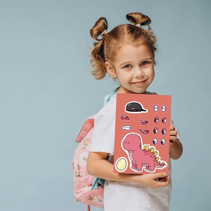 Cartoon dinosaur make-a-face sticker sheet held by a young girl on blue background