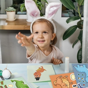 Little girl playing with cartoon dinosaur stickers for creative DIY handmade crafts