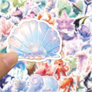 Detail of waterproof sea shell sticker with pearl held by hand showing matte finish