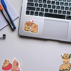 Cute capybara cartoon stickers decorating a laptop surface in a cozy workspace setup