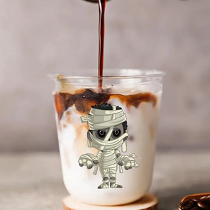 Close-up of Halloween mummy sticker on coffee cup with pouring milk latte