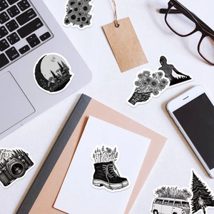 Flat lay of black and white artistic waterproof stickers on a laptop and notebook