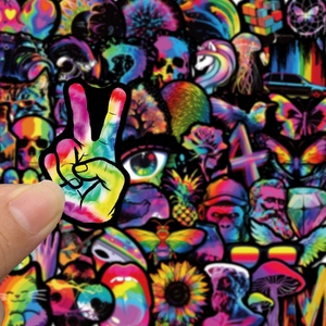 Close-up of a neon holographic graffiti sticker being held over a diverse sticker collection