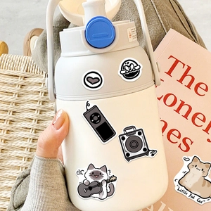 DIY cream water bottle with cute cartoon cat stickers and blue lid in a cozy handheld setting