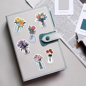 Close-up of waterproof floral jar stickers decorated on a blue notebook cover