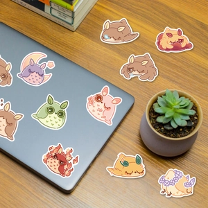 Close-up of cute cartoon owl graffiti stickers on a laptop with a cozy desk setup