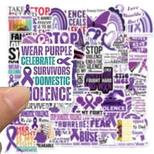 Close-up of hand holding a purple ribbon sticker for domestic violence awareness awareness