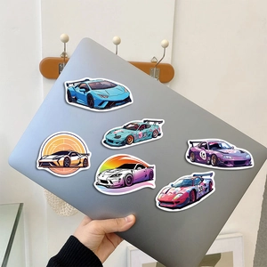Macro view of colorful cartoon supercar stickers applied on a silver laptop lid surface