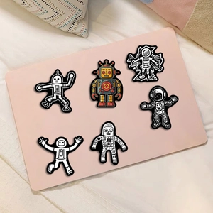 Black and white astronaut and robot cartoon stickers on a laptop surface