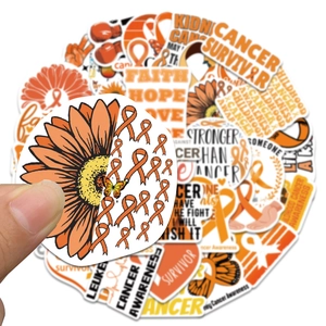 Detailed close-up showing hand holding an orange leukemia awareness sticker for DIY laptop decor